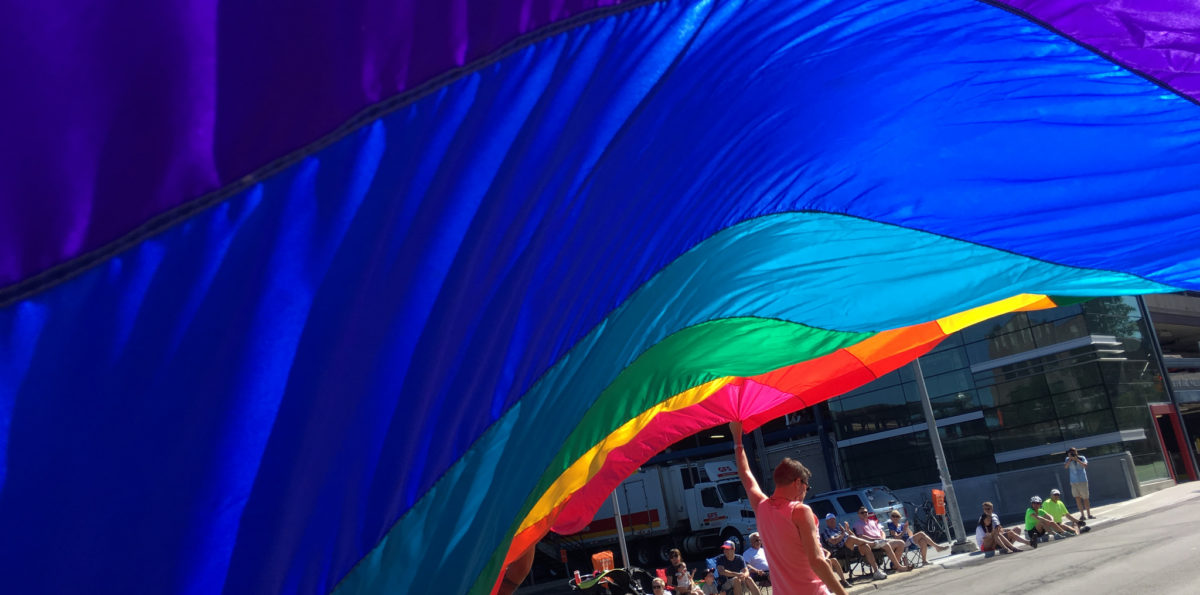 Bandeira do arco-íris sendo erguida na rua.