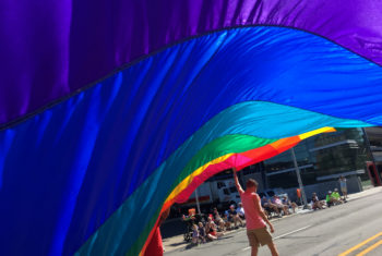 Bandeira do arco-íris sendo erguida na rua.